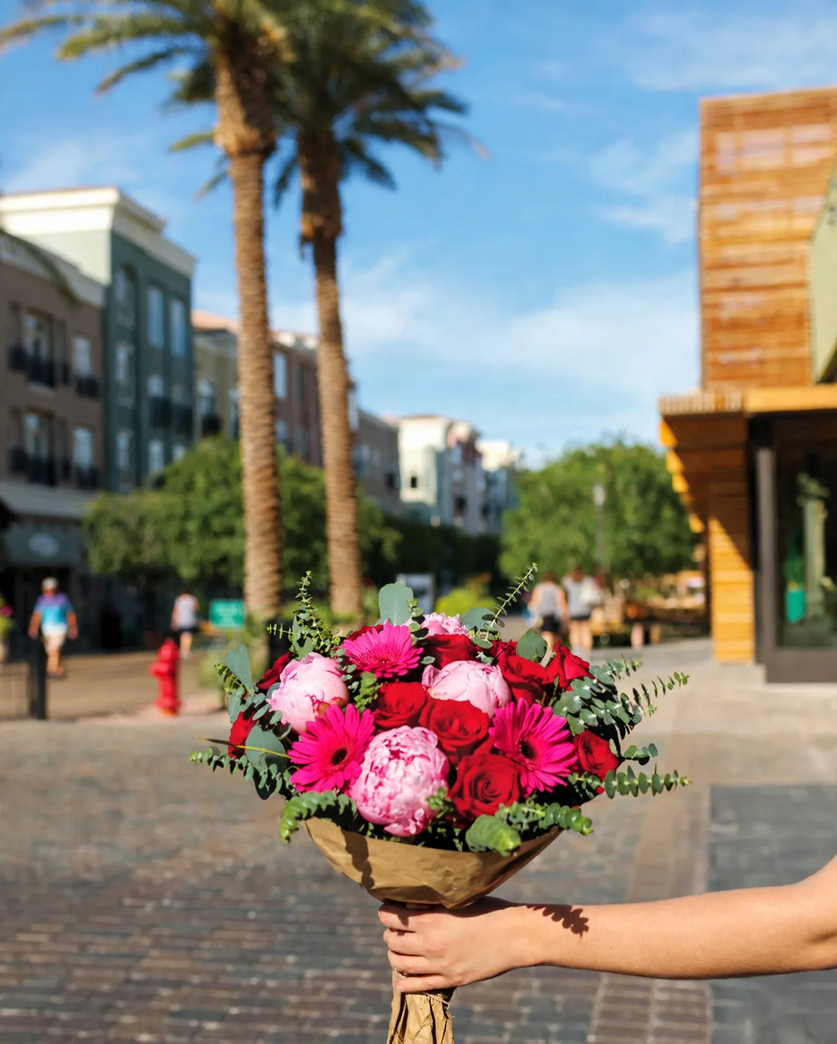 Bouquet of red roses, hot pink gerbera daisies and pink peonies held on Main Street at The District in Green Valley, Henderson