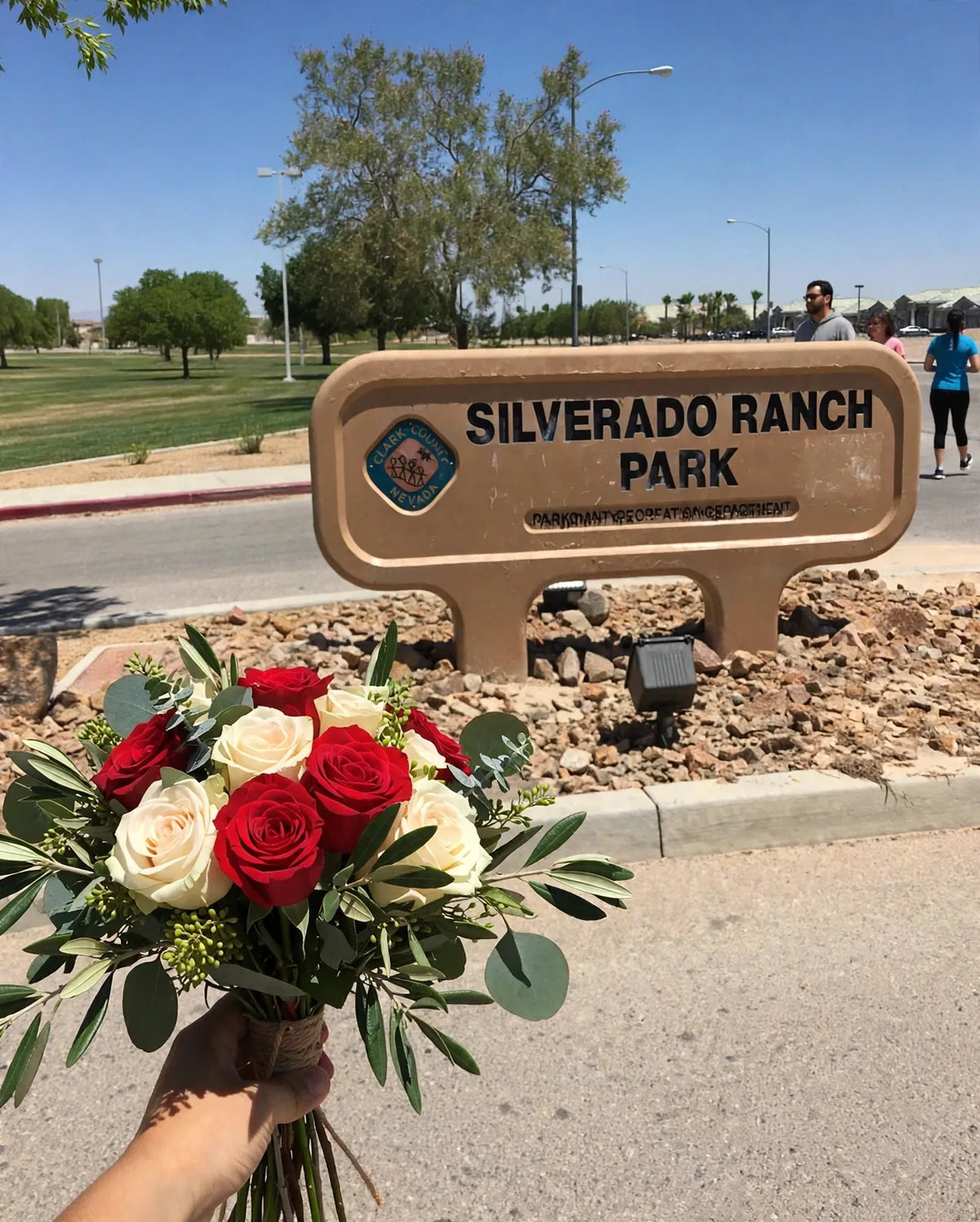 Hand-held bouquet of red and cream roses at the Silverado Ranch Park monument sign in Las Vegas