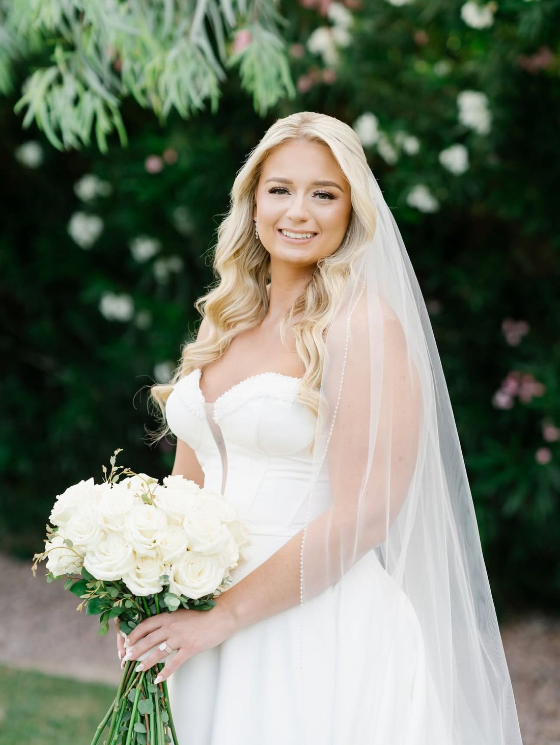 Las Vegas bride in a strapless gown and veil holding a white rose bridal bouquet