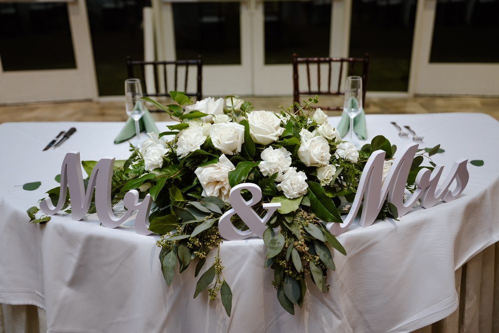 Wedding sweetheart table with a white rose and greenery garland behind a Mr and Mrs sign in Las Vegas